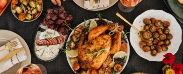 Mesa gastronómica con pollo asado, verduras, quesos, uvas y vino